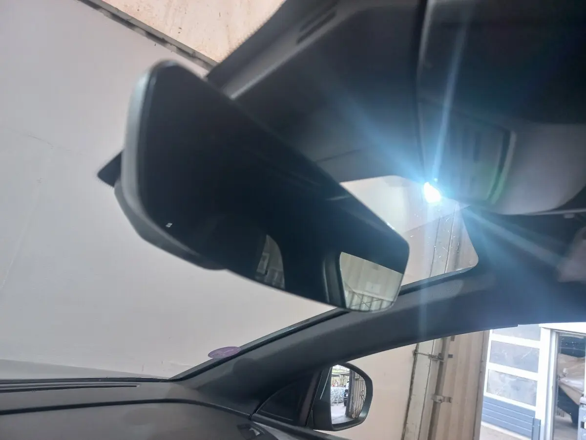 Vue intérieure du rétroviseur central et du pare-brise d’un Peugeot 3008 gris clair avec lumière naturelle entrant par le toit ouvrant.