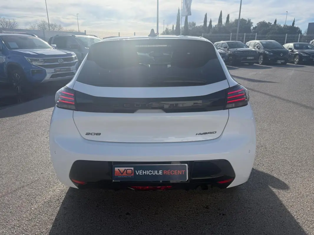 Vue arrière d'une Peugeot 208 Hybrid blanche 2024 avec feux arrière LED et bande noire distinctive.
