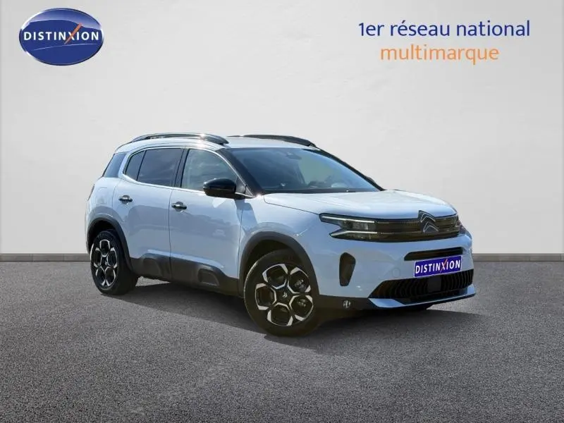 Vue 3/4 avant droite du Citroën C5 Aircross blanc Okénite avec jantes distinctives et toit noir contrasté.