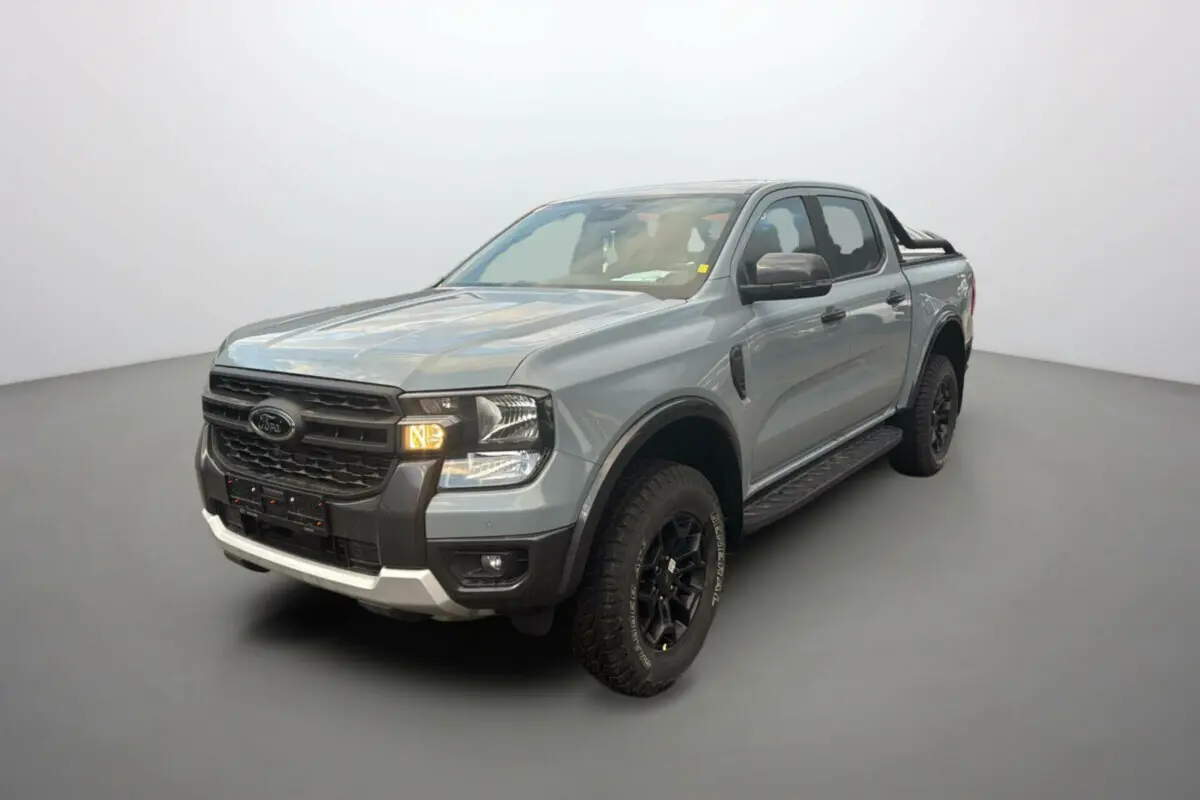 Ford Ranger gris commandeur en 3/4 avant droit avec arceaux noirs et marchepieds visibles sur fond neutre.
