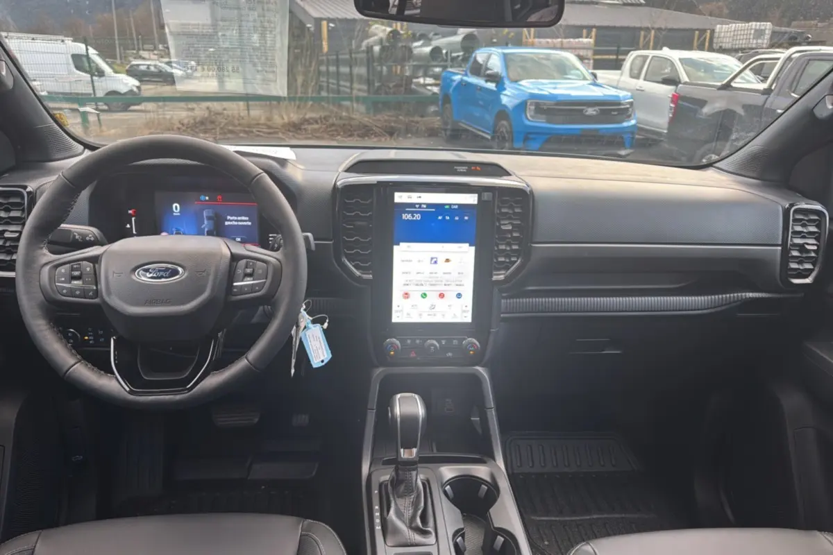 Vue intérieure avant du Ford Ranger 2026 avec tableau de bord noir et écran tactile vertical lumineux.