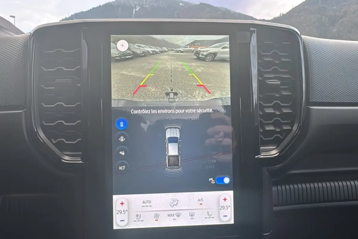 Vue rapprochée de l’écran central tactile du Ford Ranger gris Commandeur affichant la caméra de recul et les réglages climatiques.