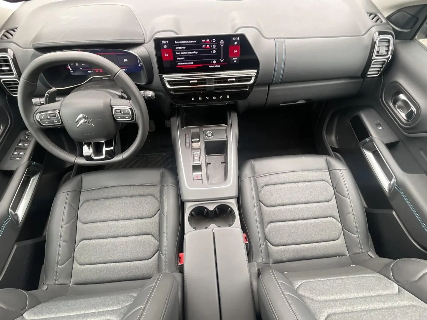 Vue intérieure avant du Citroën C5 Aircross 2025, sièges gris et noir avec tableau de bord numérique et écran tactile central.