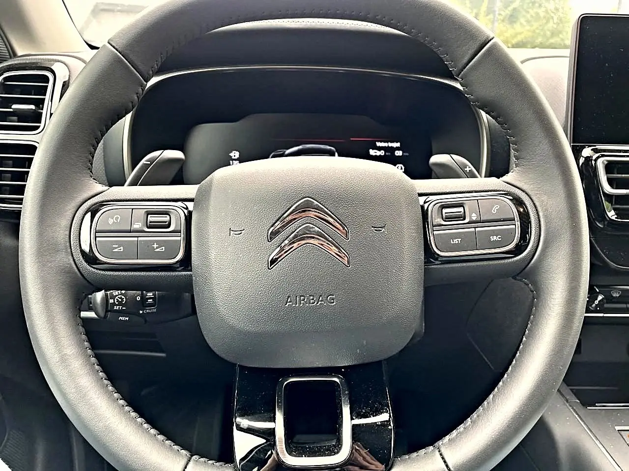 Vue rapprochée du volant noir du Citroën C5 Aircross 2025 avec commandes multifonctions et logo chromé central.