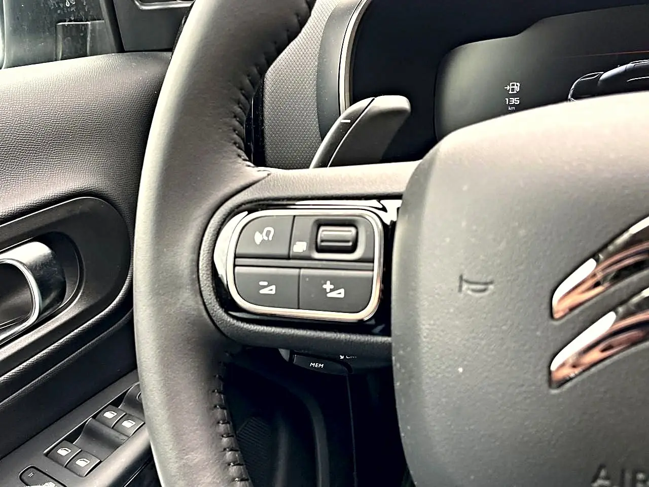 Gros plan sur le volant noir de la Citroën C5 Aircross 2025, avec commandes intégrées côté gauche et logo chromé visible.