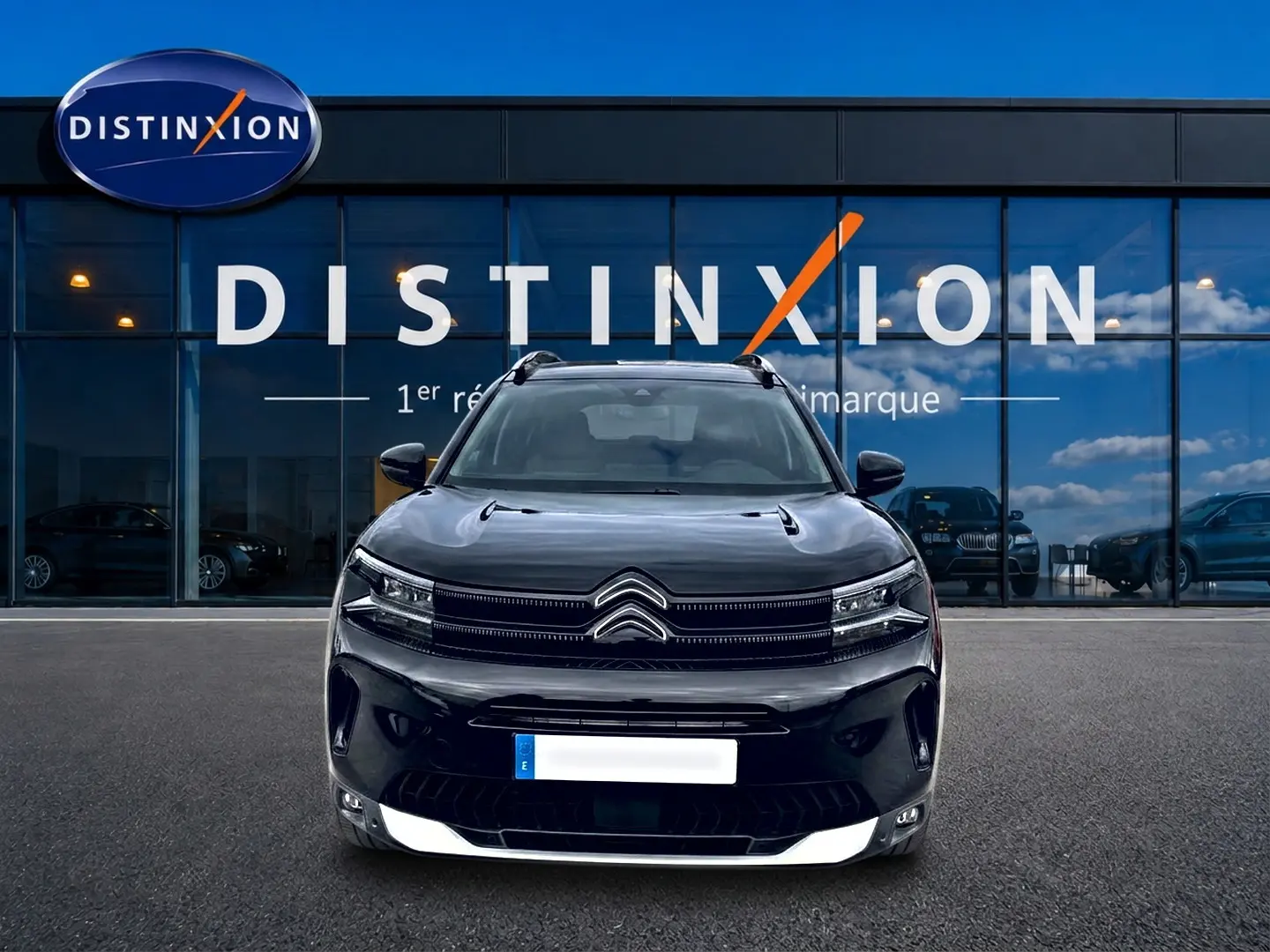 Vue frontale d’un Citroën C5 Aircross noir 2025, avec calandre distinctive et phares LED, devant une vitrine bleue.
