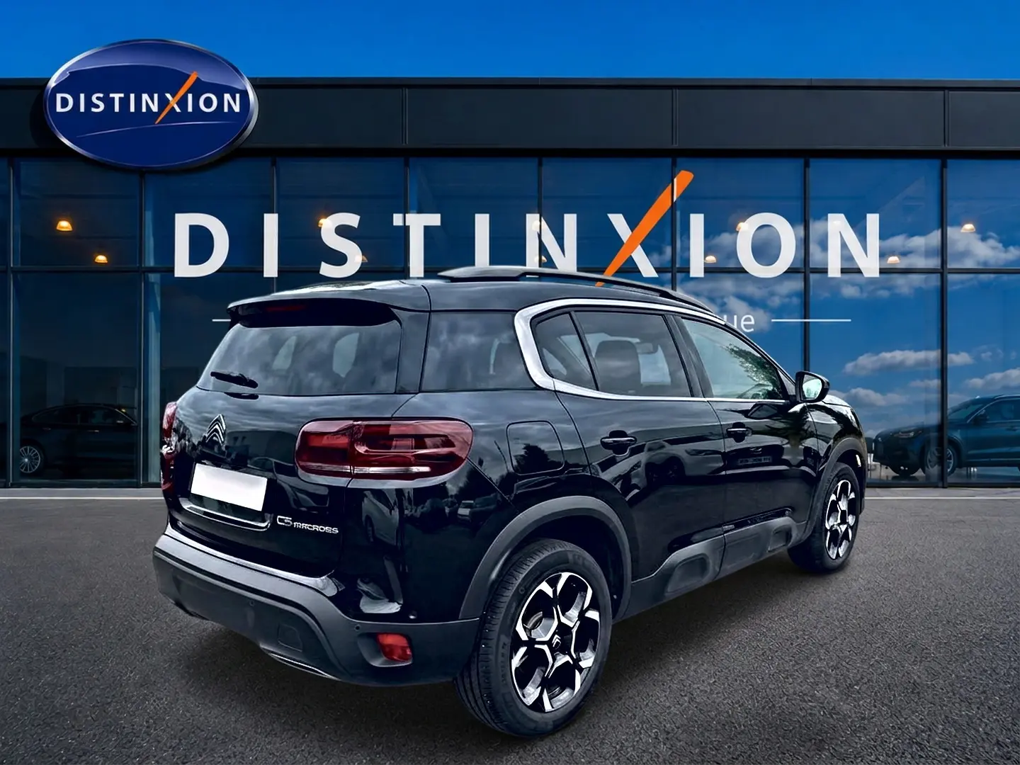 Vue 3/4 arrière droite d’un Citroën C5 Aircross noir avec jantes alu et vitres teintées devant un showroom Distinxion.
