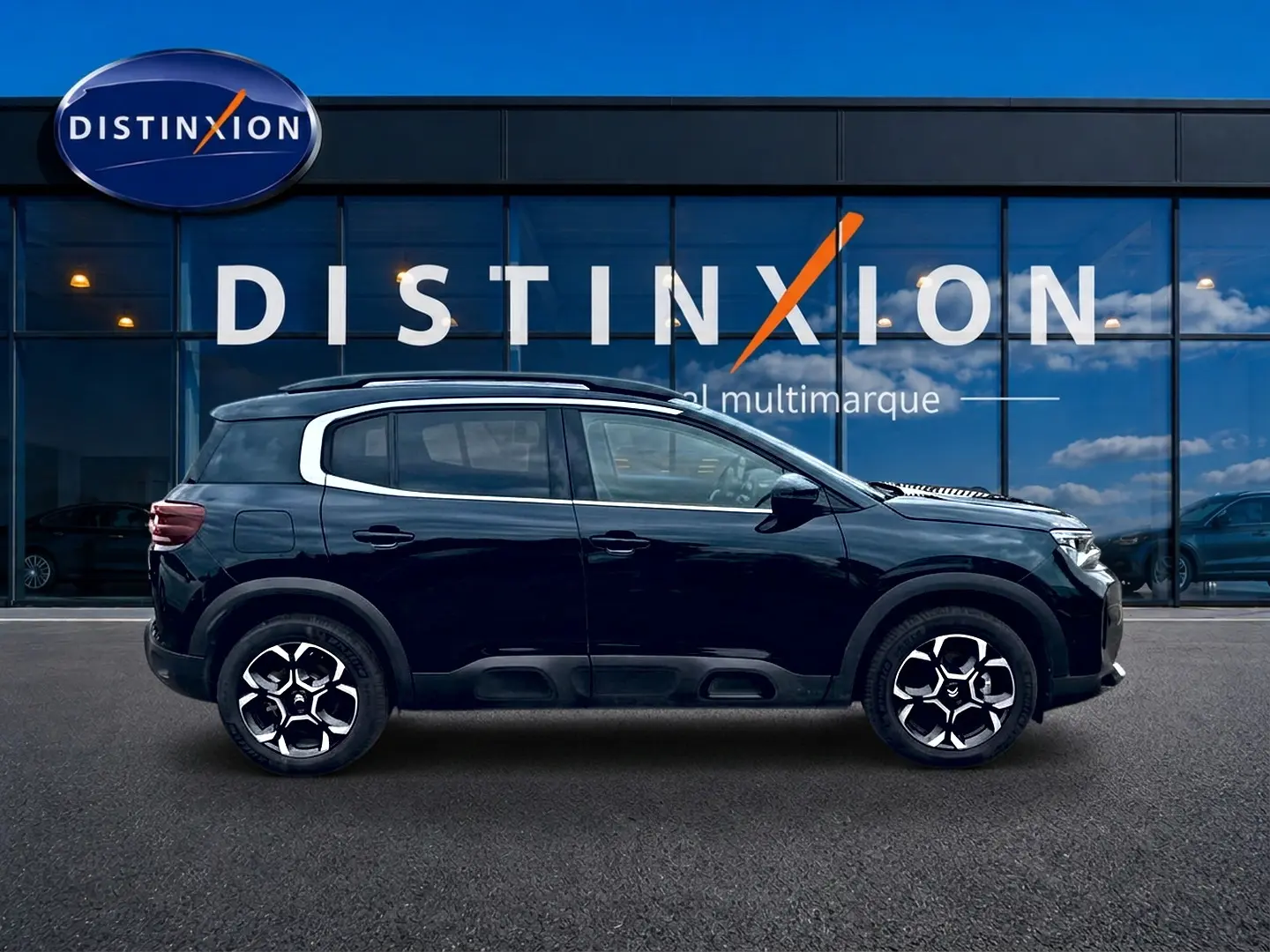 Profil droit d'un Citroën C5 Aircross noir 2025 avec jantes alu et barres de toit, devant une vitrine Distinxion.