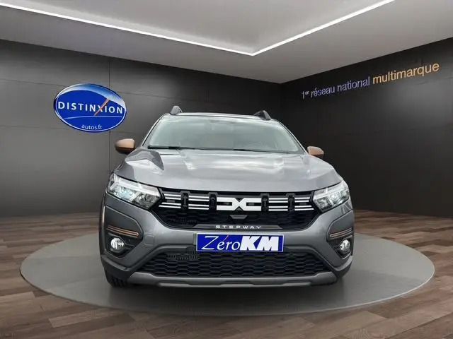 Vue frontale du Dacia Sandero Stepway TCE 110 Extreme Plus gris Urban avec feux LED et barres de toit noires visibles.