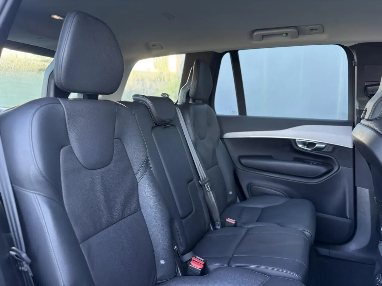 Vue intérieure côté droit des sièges arrière en cuir noir du Volvo XC90 T8 AWD 2024, ambiance lumineuse naturelle.