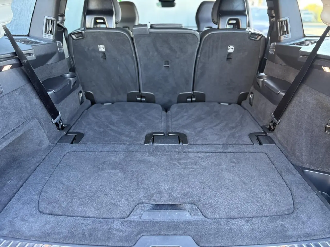 Coffre spacieux du Volvo XC90 T8 gris Platinium, sièges arrière rabattus, vue depuis l'arrière intérieur.