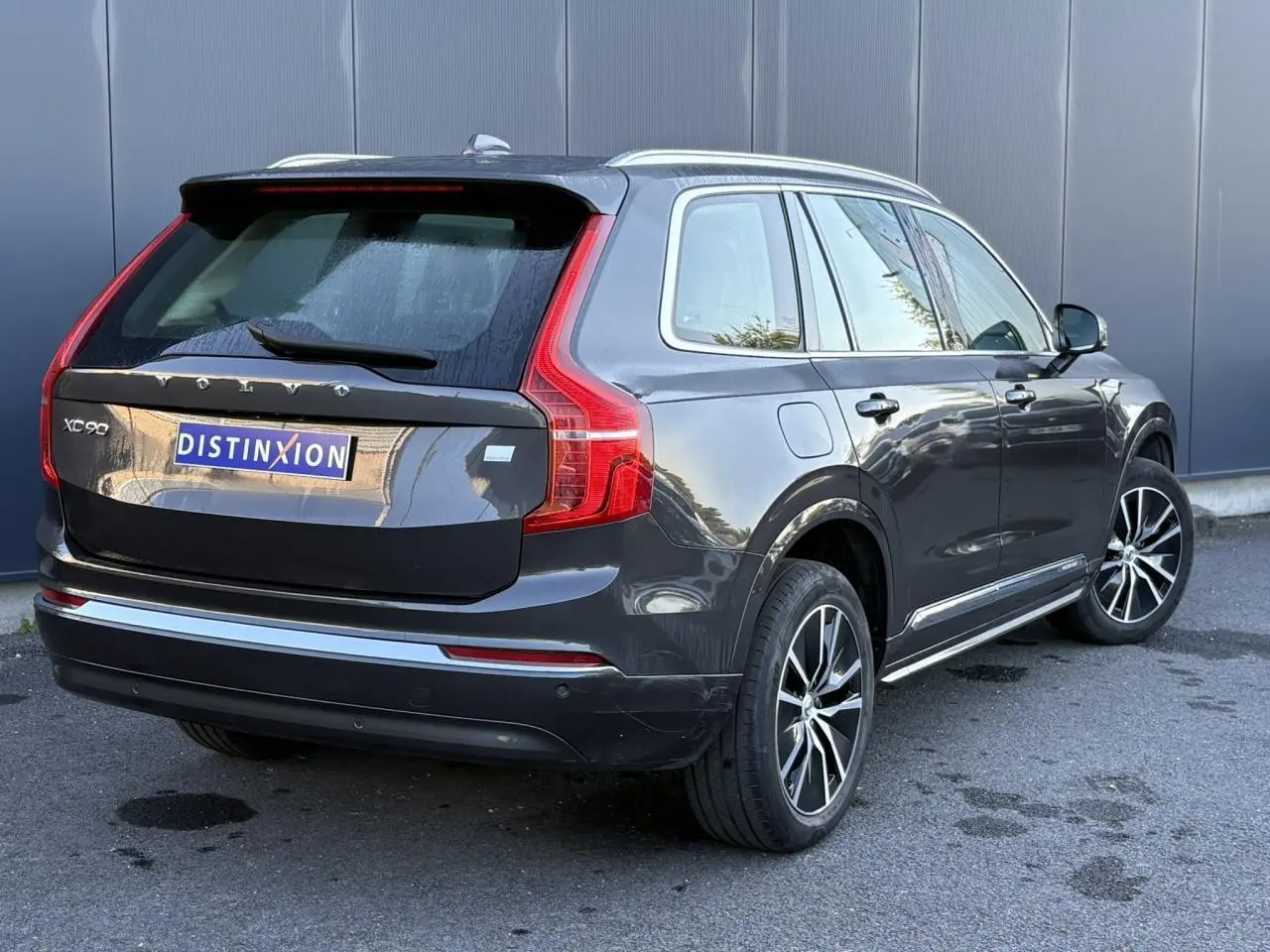 Vue 3/4 arrière droite d'un Volvo XC90 gris Platinium avec jantes alliage et feux arrière LED distinctifs.