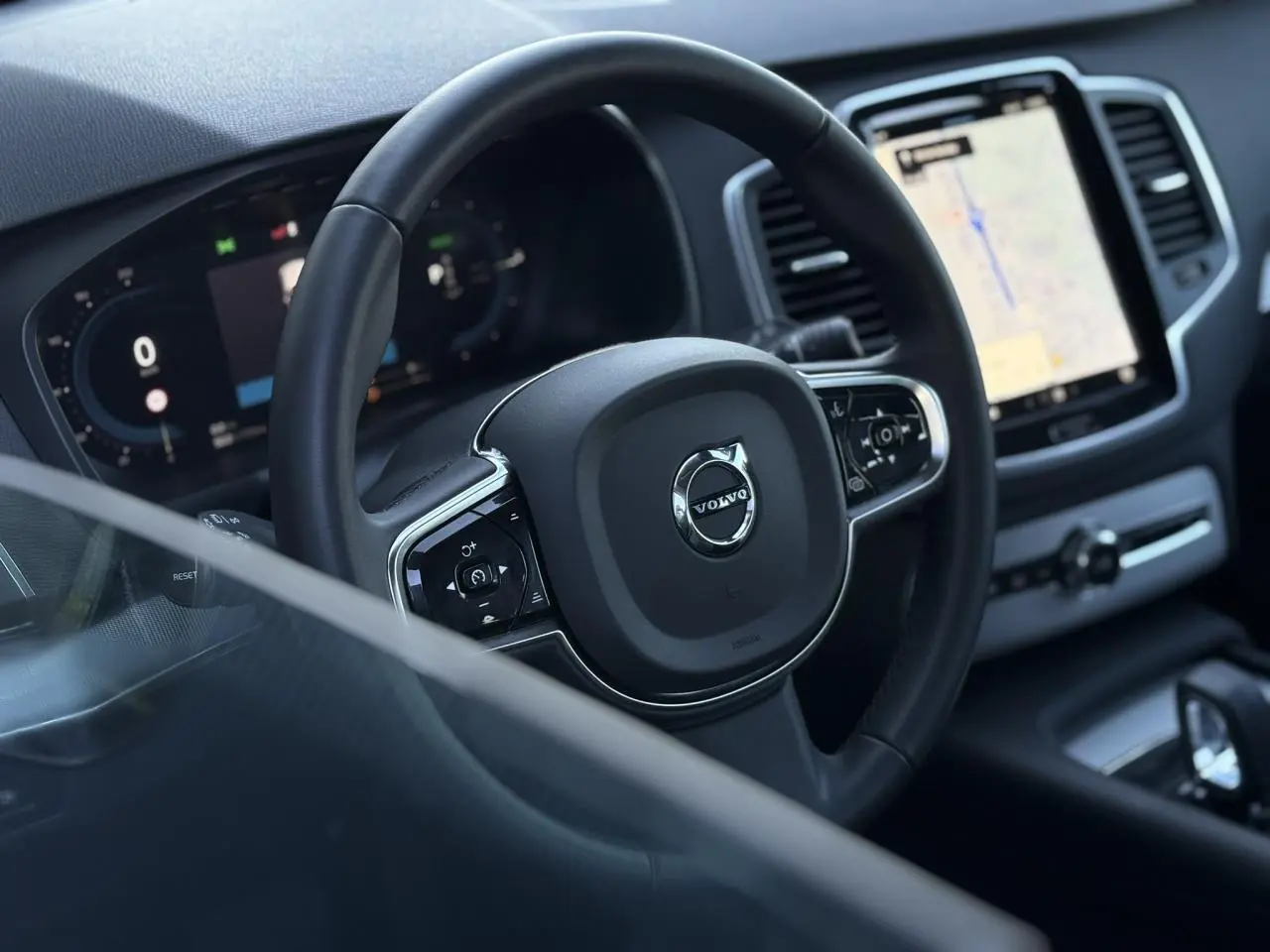 Vue rapprochée du volant et du tableau de bord digital du Volvo XC90 T8 hybride avec écran tactile central.