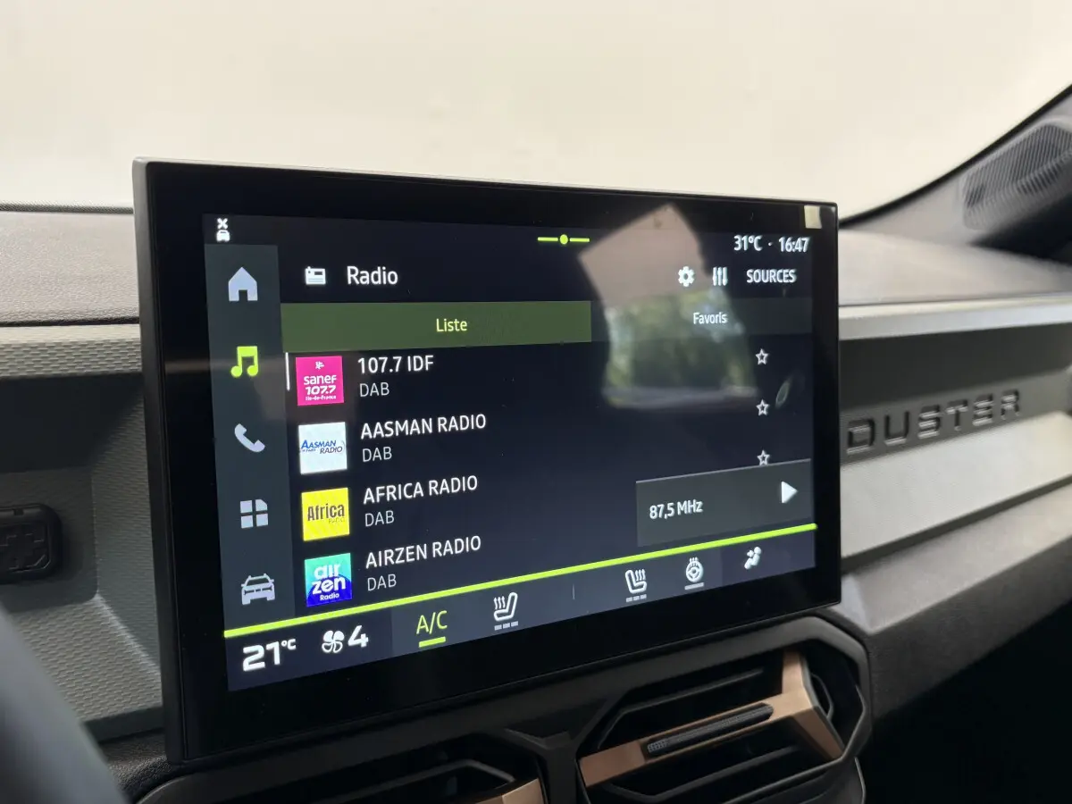 Écran tactile central affichant la radio dans l'habitacle du Dacia Duster noir, tableau de bord avec logo Duster visible
