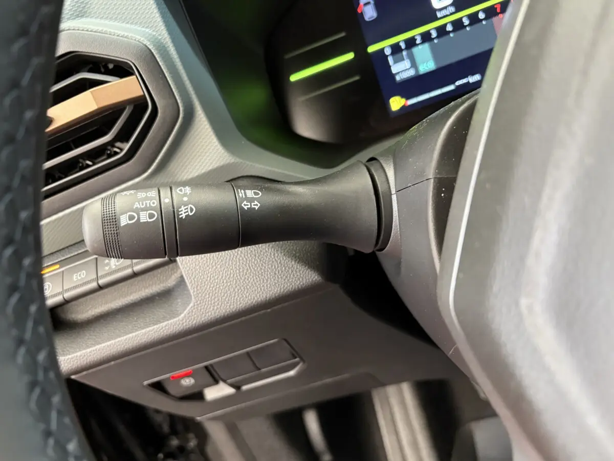 Gros plan sur la manette de phares et clignotants du tableau de bord du Dacia Duster noir 2025, version hybride.