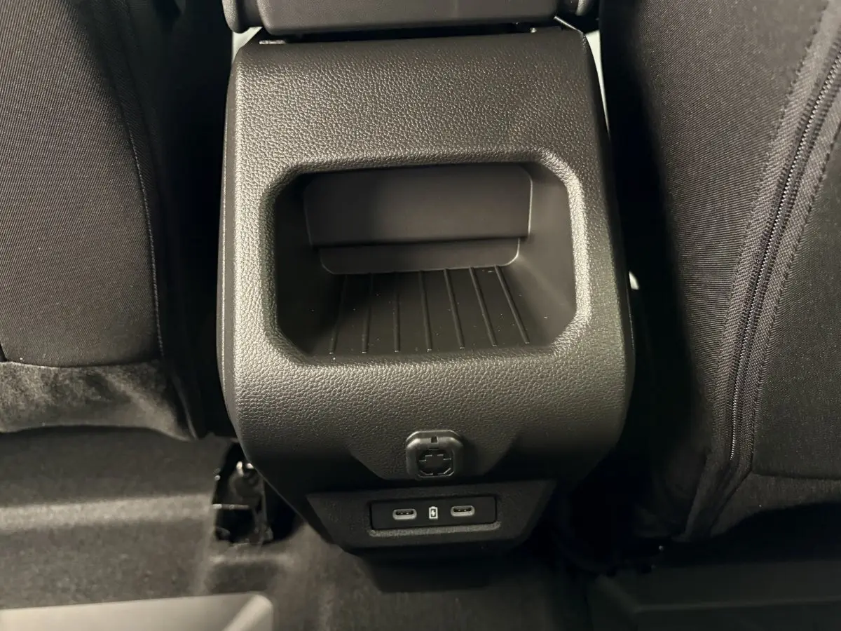 Prise USB double et rangement arrière noir dans l'habitacle du Dacia Duster 2025 vue de face entre les sièges arrière.