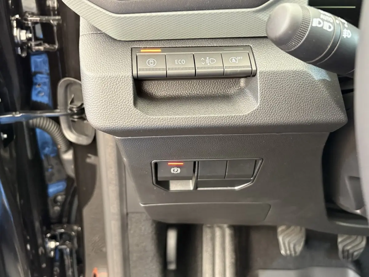 Vue rapprochée des commandes côté gauche du tableau de bord du Dacia Duster noir, avec boutons ECO et frein à main électrique.