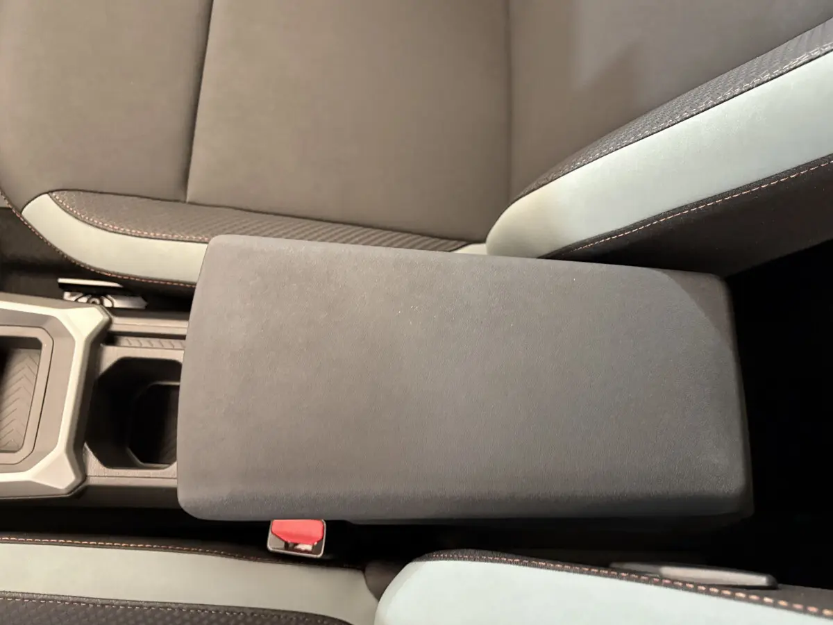 Accoudoir central noir et sièges bicolores gris et noir du Dacia Duster 2025 vue de dessus côté intérieur.