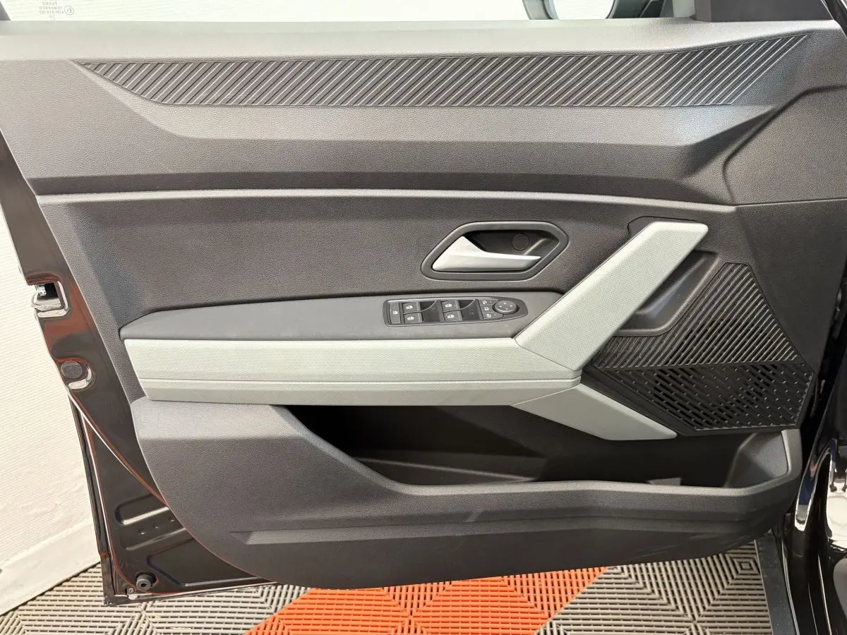 Porte côté gauche ouverte du Dacia Duster noir 2025, montrant les commandes de vitres et le design intérieur moderne.