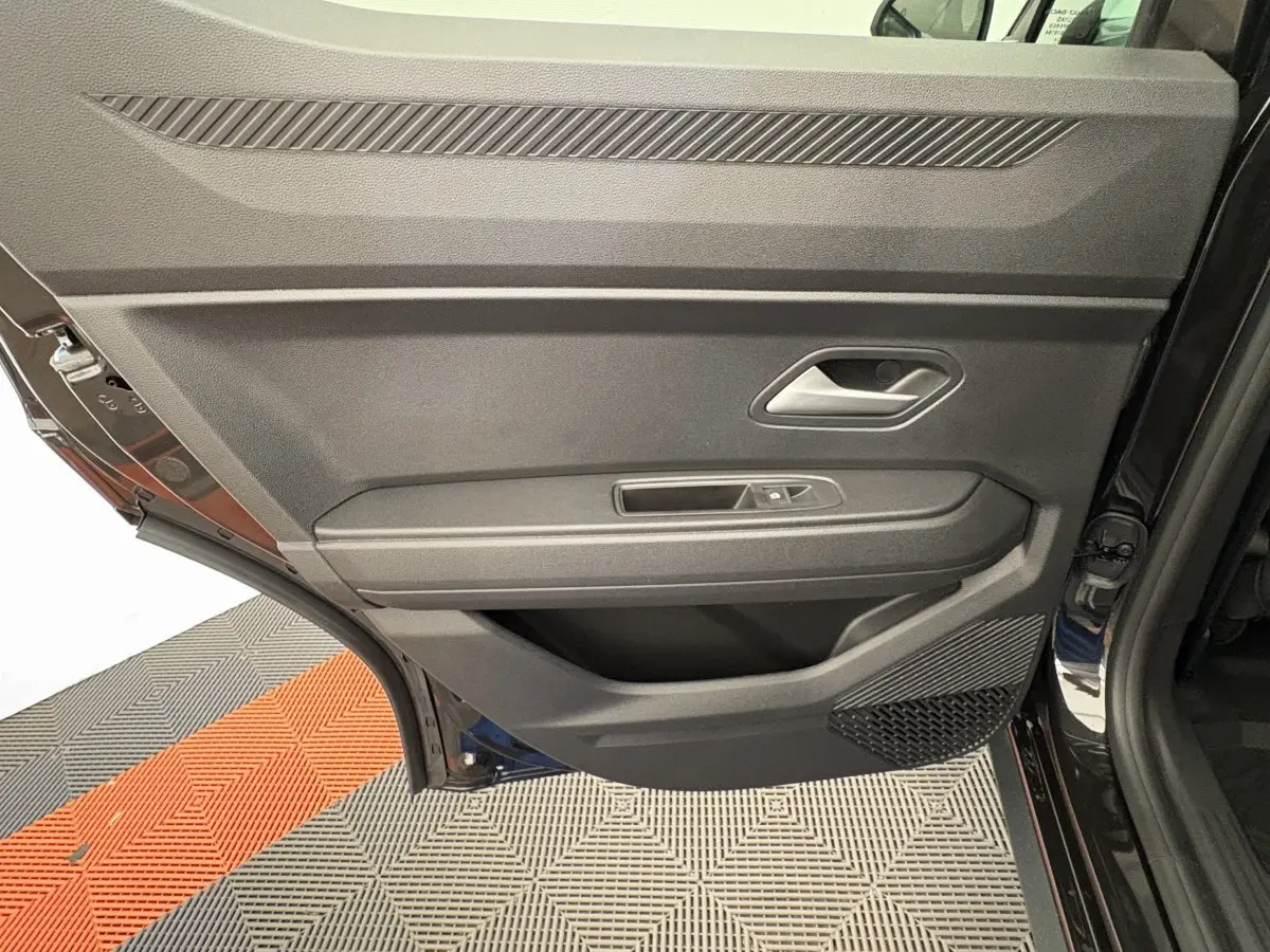 Gros plan sur la porte arrière gauche noire du Dacia Duster 2025 avec poignée et commande de vitre intégrées.