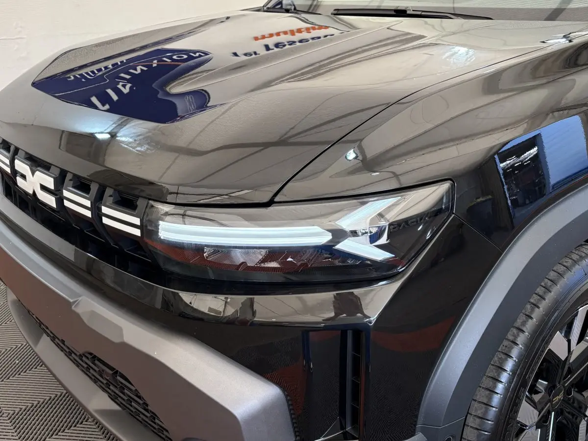 Gros plan sur l'avant droit noir du Dacia Duster 2025 avec phares LED et calandre distinctive.