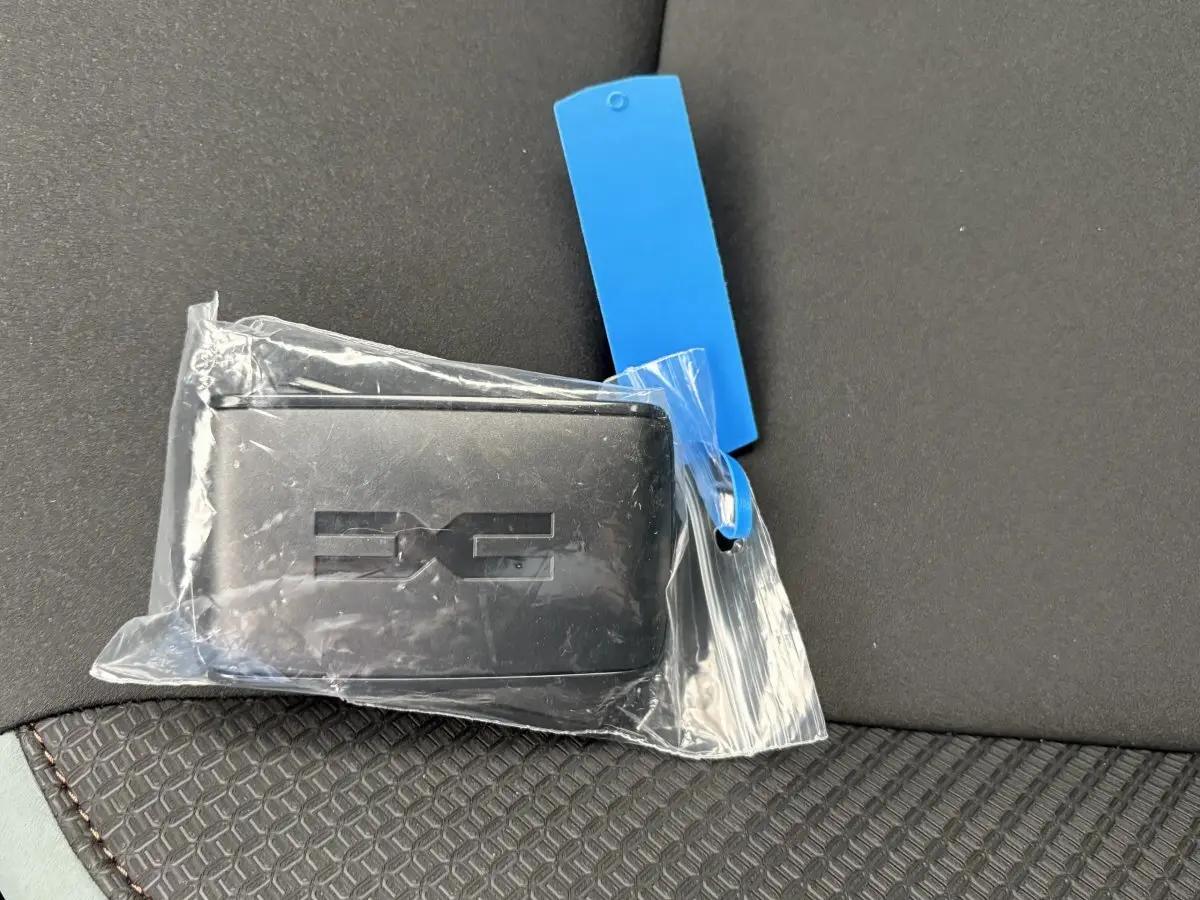 Clé noire Dacia Duster Extreme Mild Hybrid posée sur un siège tissu noir avec surpiqûres marron.