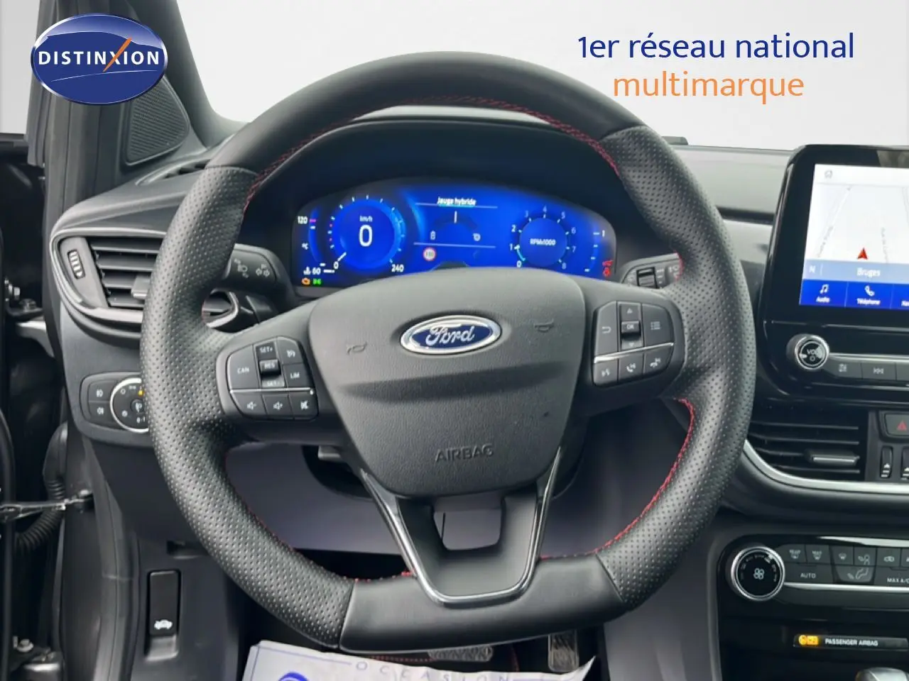 Vue rapprochée du volant perforé avec surpiqûres rouges et tableau de bord numérique du Ford Puma gris magnétique 2024.