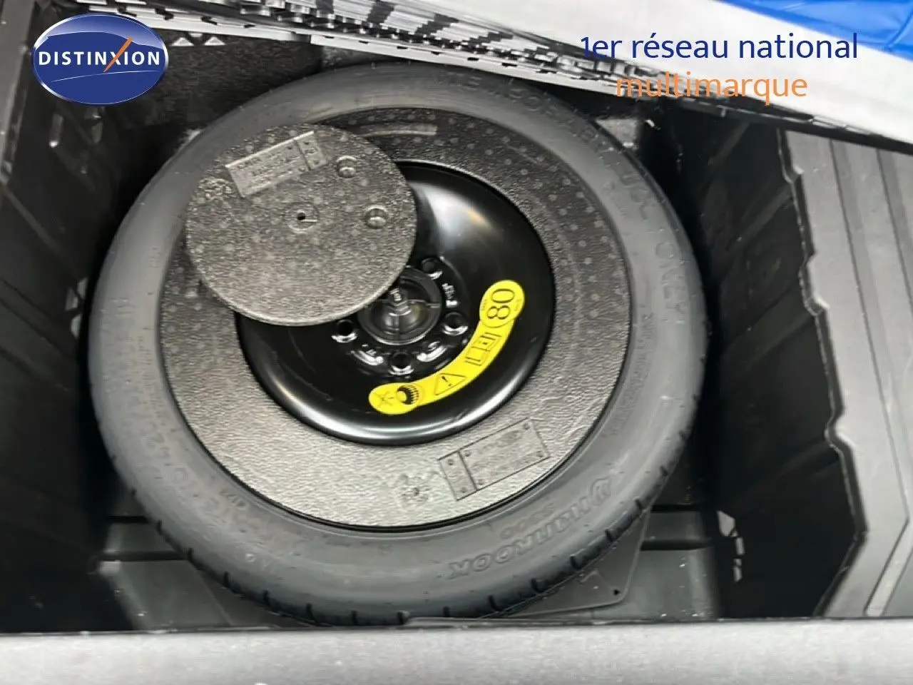 Roue de secours compacte dans le coffre du Ford Puma gris magnétique 2024, vue plongeante sur le pneu de secours.