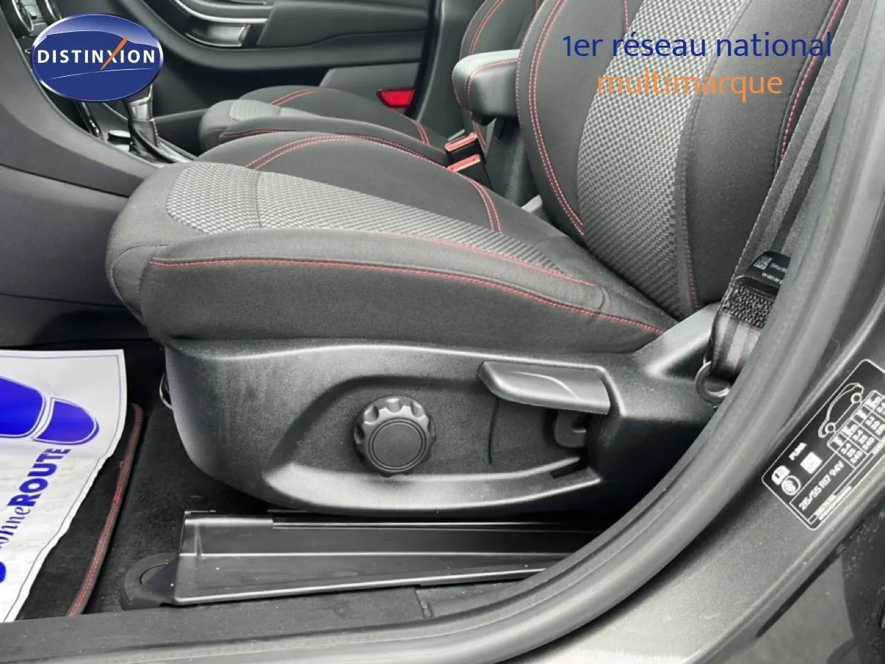 Gros plan sur le siège avant droit du Ford Puma gris magnétique 2024 avec surpiqûres rouges et réglages manuels visibles.