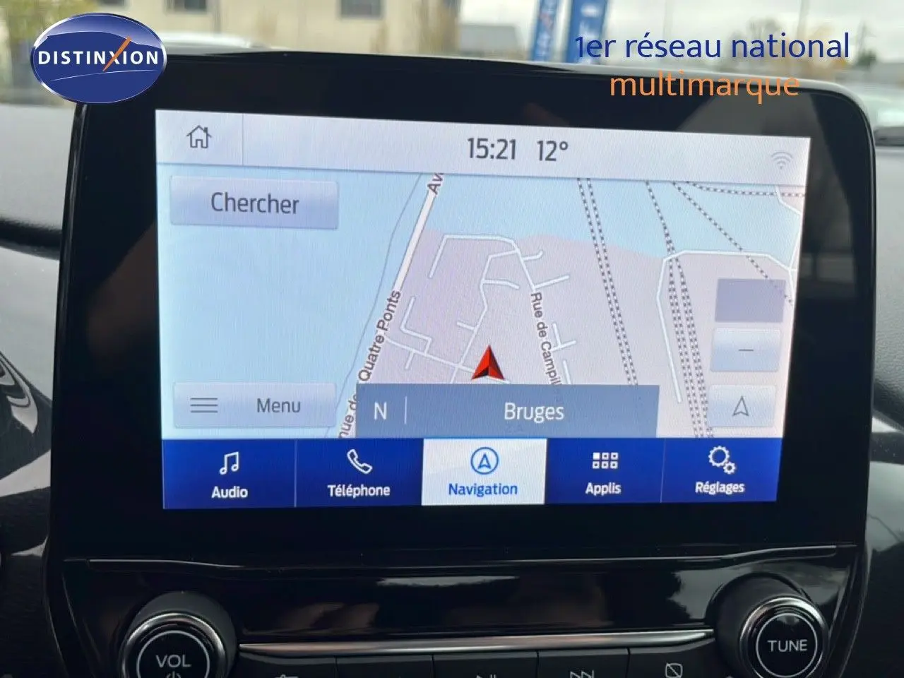 Écran tactile central du Ford Puma gris magnétique 2024 affichant la navigation vers Bruges en intérieur lumineux.