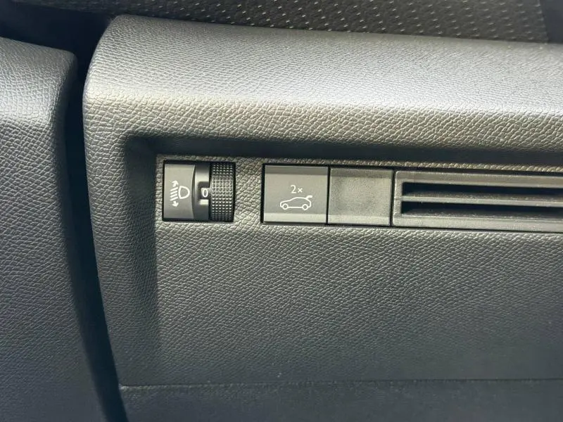 Détail intérieur montrant les commandes de réglage des phares et ouverture du coffre sur un Citroën C4 X gris Mercury.