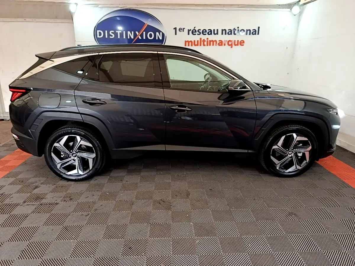 Vue latérale droite d'un Hyundai Tucson gris foncé 2022 avec jantes alliage et toit noir dans un showroom.