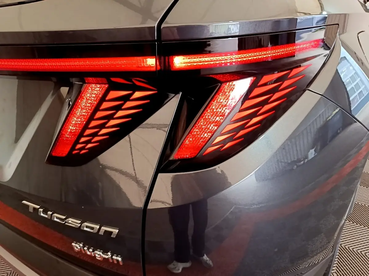 Gros plan sur le feu arrière droit allumé du Hyundai Tucson gris foncé avec logo et éclairage LED distinctif.