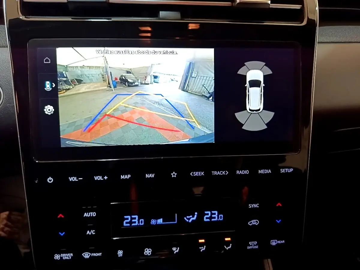 Écran tactile central affichant la caméra de recul avec guidage et capteurs de stationnement du Hyundai Tucson gris foncé.