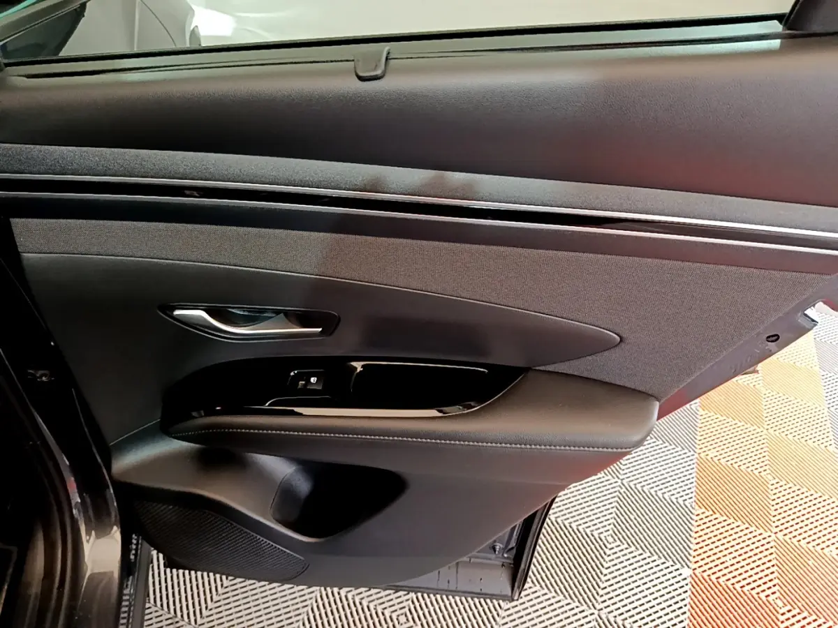 Vue intérieure de la porte arrière droite du Hyundai Tucson 2022, revêtement noir avec commande de fenêtre intégrée.