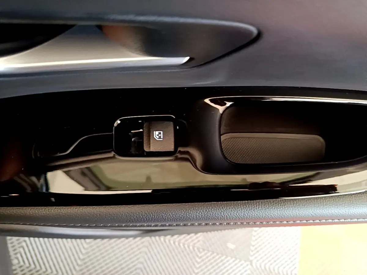Gros plan sur la commande de verrouillage des vitres côté conducteur du Hyundai Tucson gris foncé, finition intérieure noire brillante.