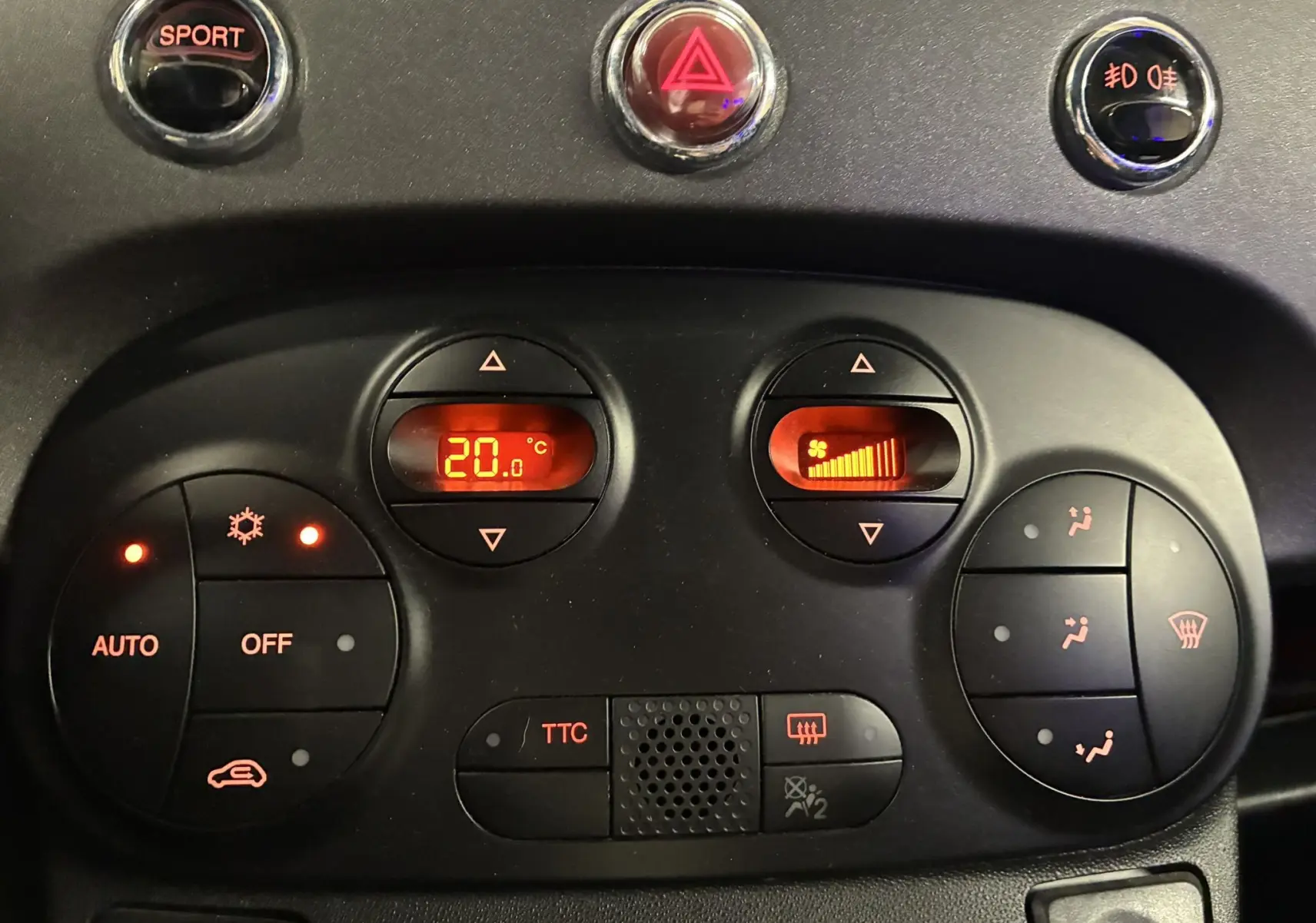 Vue rapprochée du tableau de bord de l'Abarth 500 Competizione 2016, avec commandes de climatisation et bouton sport rouge et gris.