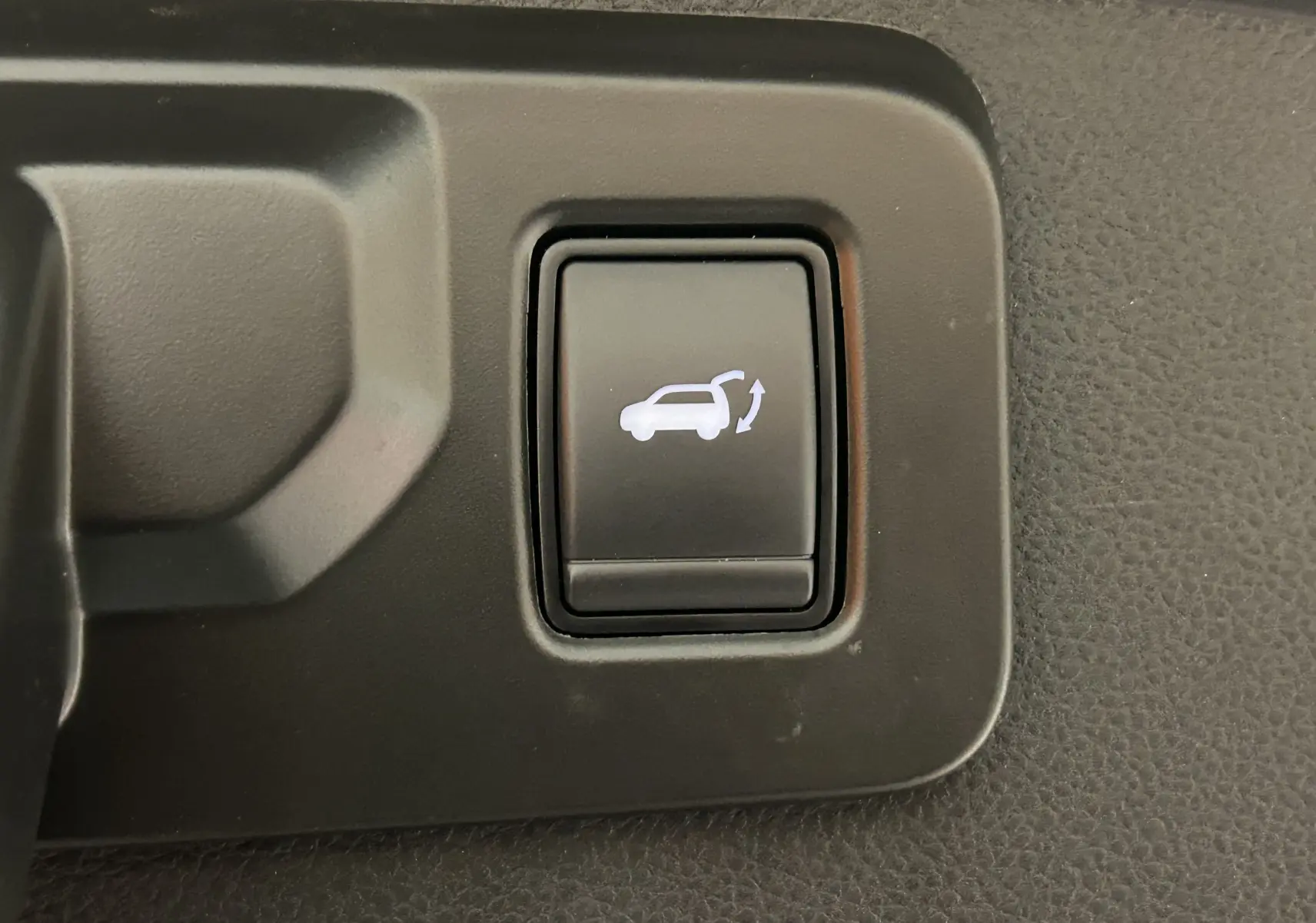 Bouton intérieur noir avec symbole blanc d'ouverture de hayon sur Renault Austral E-Tech blanc nacré.