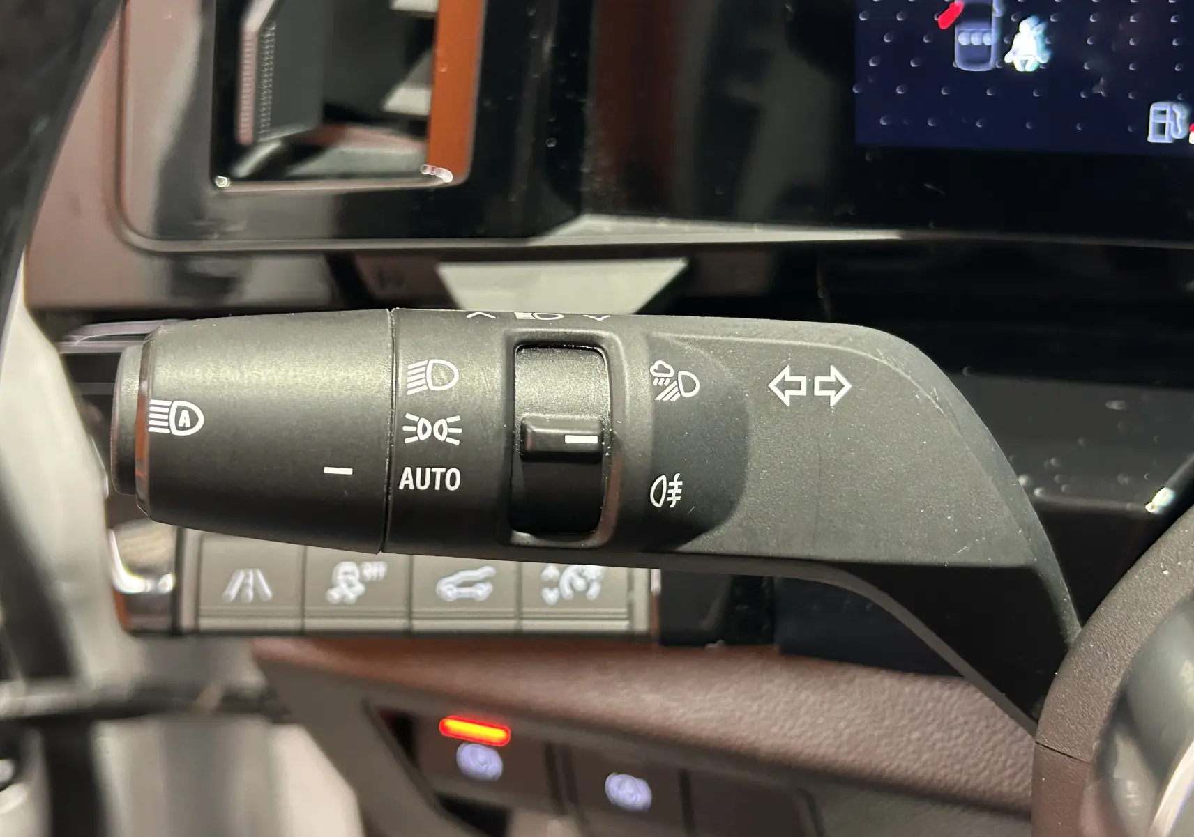 Gros plan sur la manette de clignotants et feux à gauche du volant dans l’habitacle du Renault Austral blanc nacré 2024.