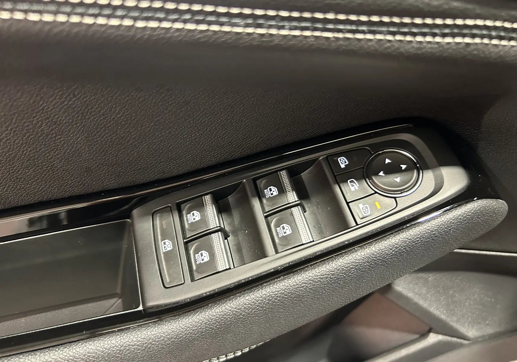 Gros plan sur les commandes de lève-vitres et rétroviseurs côté conducteur d’un Renault Austral 2024 noir.