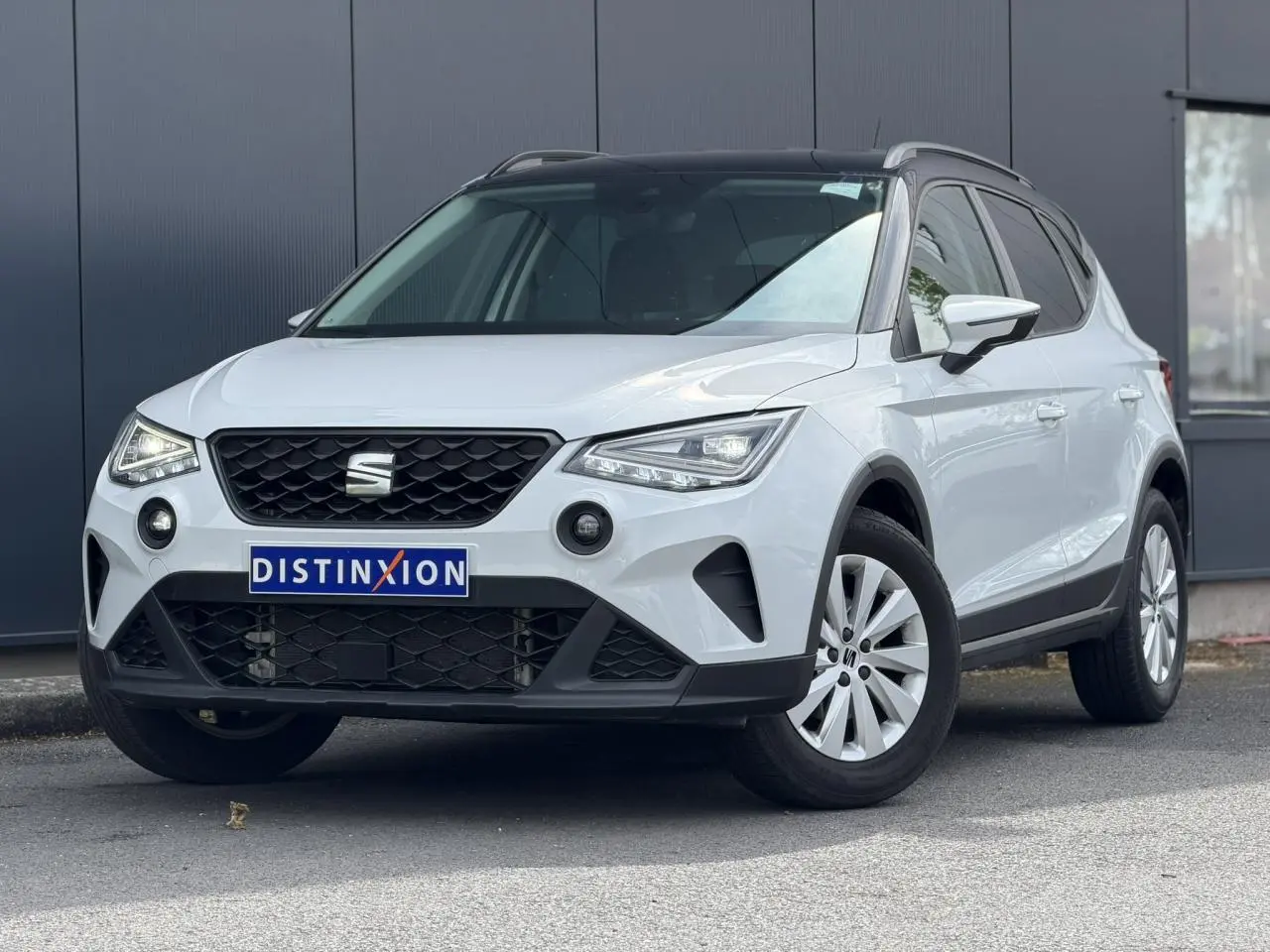 Vue 3/4 avant d'un SEAT Arona blanc alpin avec toit noir, calandre noire et jantes alliage 16 pouces.