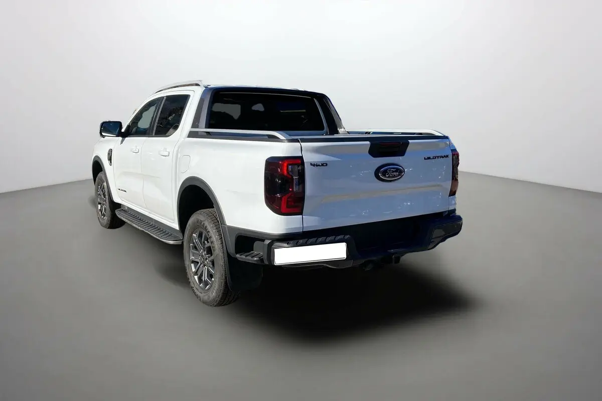 Ford Ranger 2025 blanc glacier en 3/4 arrière droit, avec logo Wildtrak et feux arrière foncés visibles