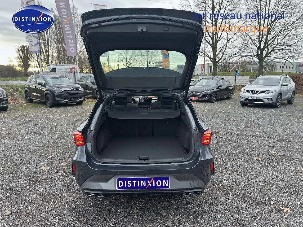 Vue arrière d'une CUPRA LEON ST gris magnétique avec coffre ouvert sur parking extérieur.