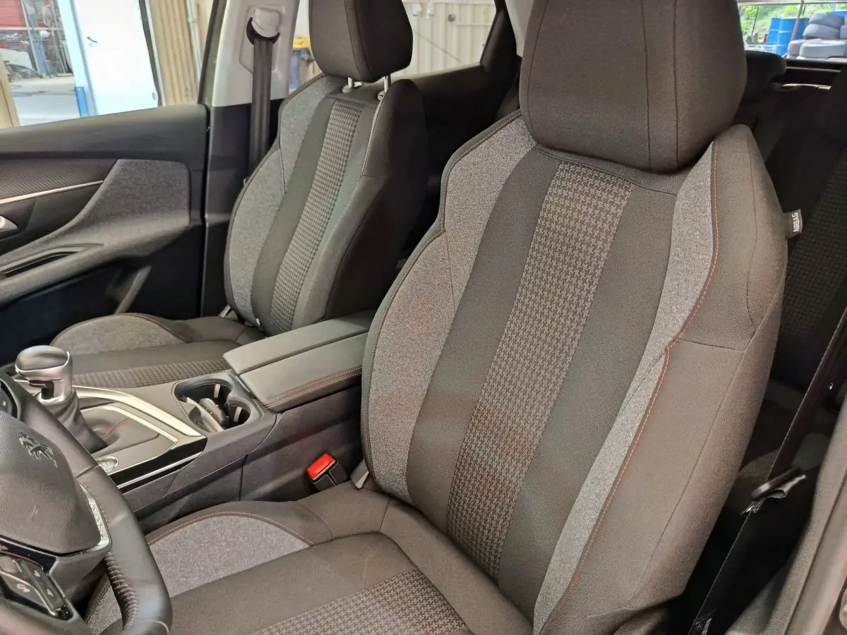 Vue rapprochée des sièges avant en tissu gris du Peugeot 3008 Puretech 130 S&S Active Business 2020, avec console centrale.