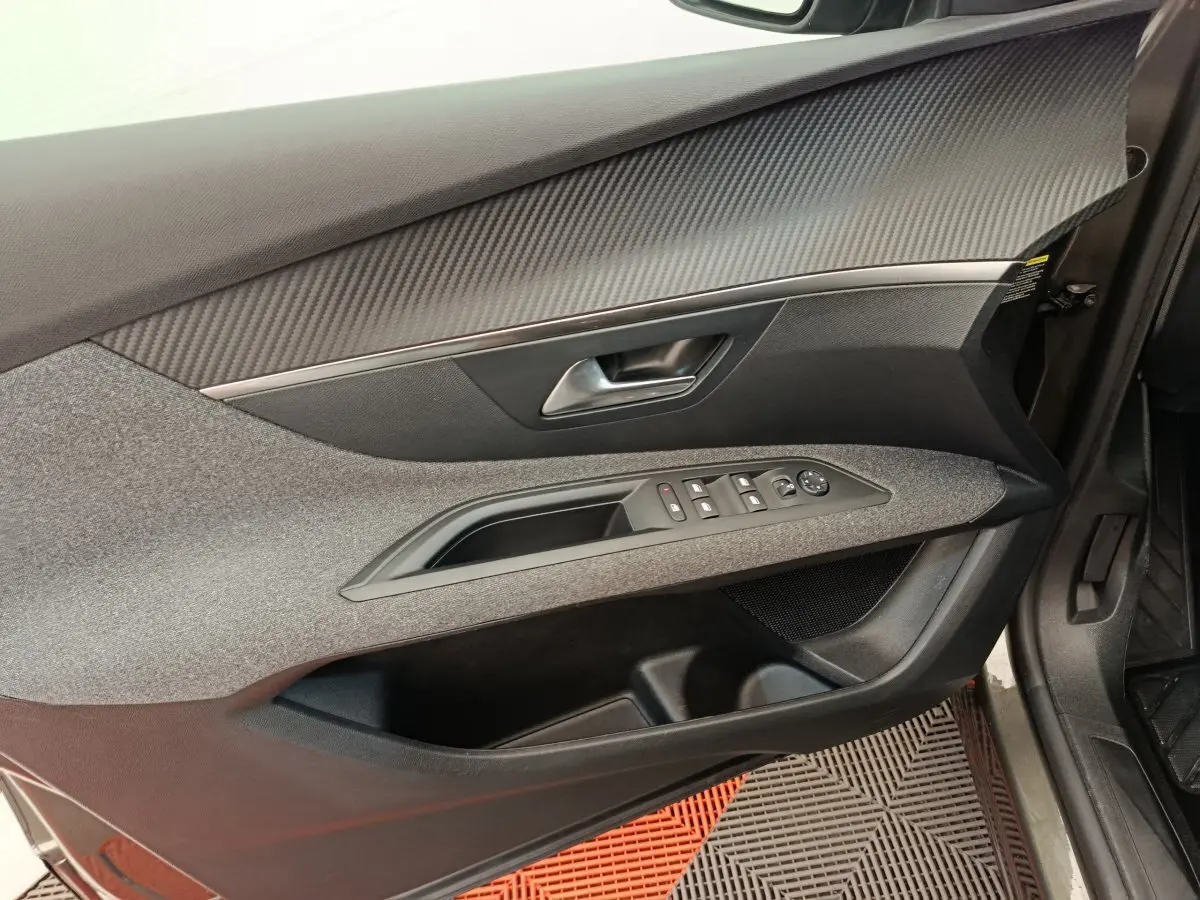 Intérieur côté gauche de la porte avant d’un Peugeot 3008 gris foncé, avec commandes électriques et finition tissu.