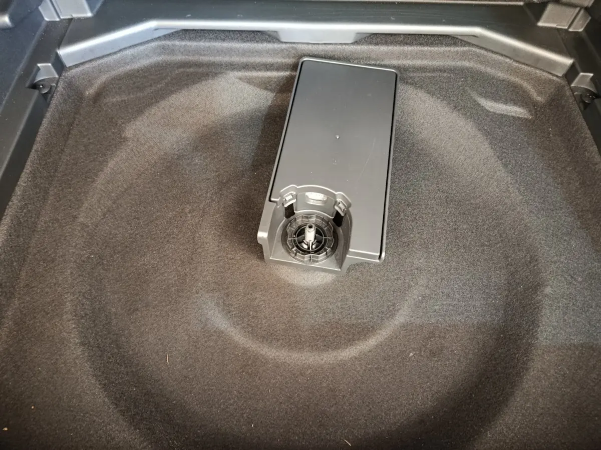 Gros plan sur le rangement sous tablette du coffre du Peugeot 3008 gris foncé, montrant un support central.