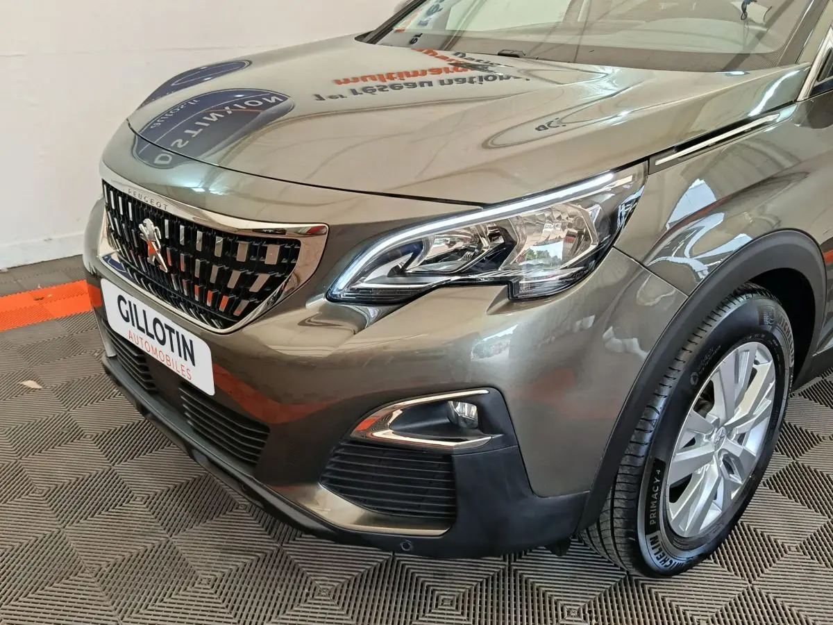 Vue 3/4 avant droit d'un Peugeot 3008 gris foncé avec calandre chromée et feux LED distinctifs.