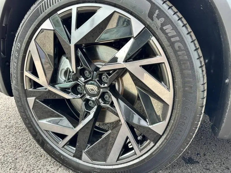 Gros plan sur la roue avant droite du Renault Captur 2025 esprit Alpine avec jante noire et argentée au design géométrique.