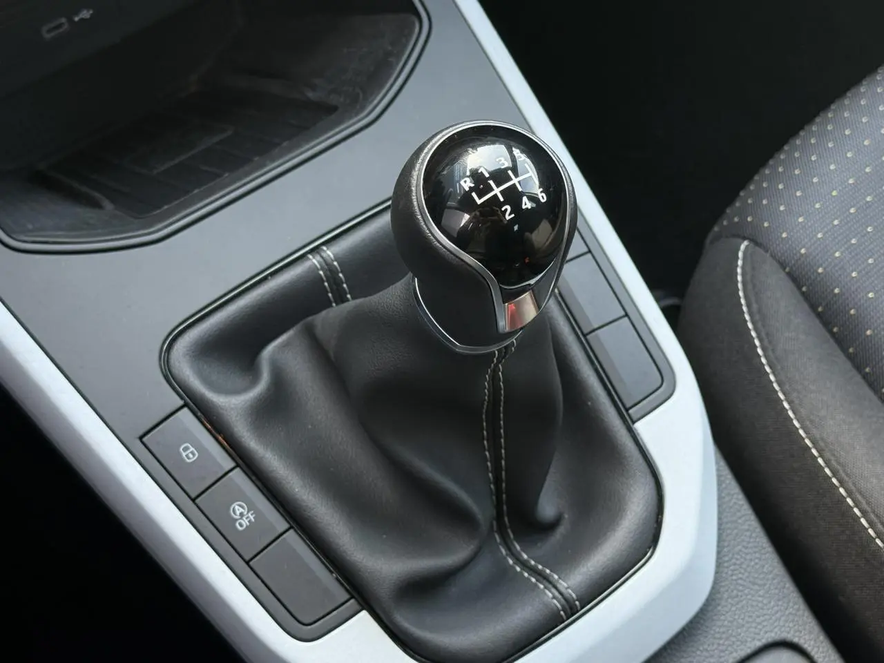 Gros plan sur le levier de vitesses manuel noir avec coutures blanches dans l’habitacle du SEAT Arona TSI 115 Style 2025.