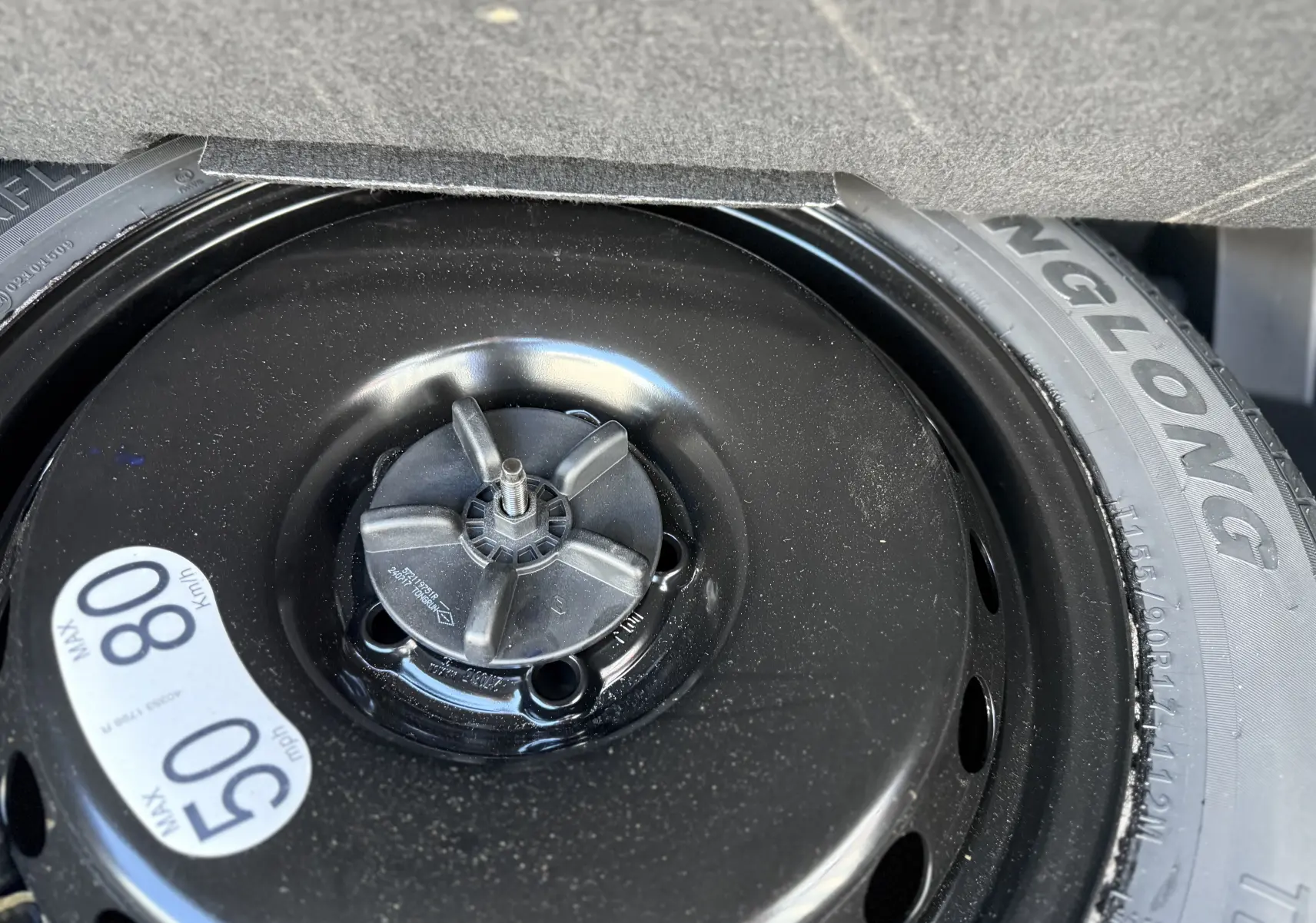 Gros plan sur la roue de secours noire du Renault Austral 2025, visible dans le coffre, avec étiquette de vitesse maximale.